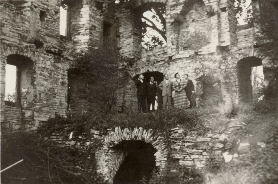 Eine Besuchergruppe betrachtet die Ruine des Herrenhause (ca. 1930).